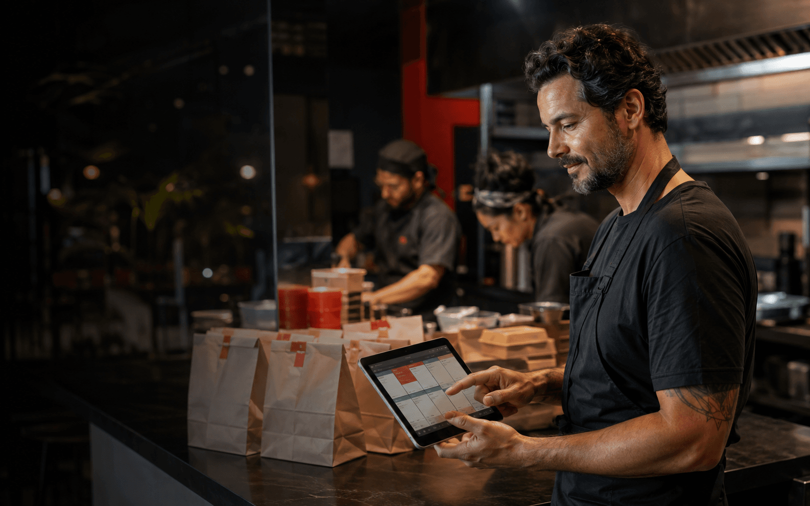 Gestora de restaurante acompanhando pedidos em um tablet na cozinha